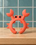 Red silicone crab utensil rest with raised claws on a wooden counter