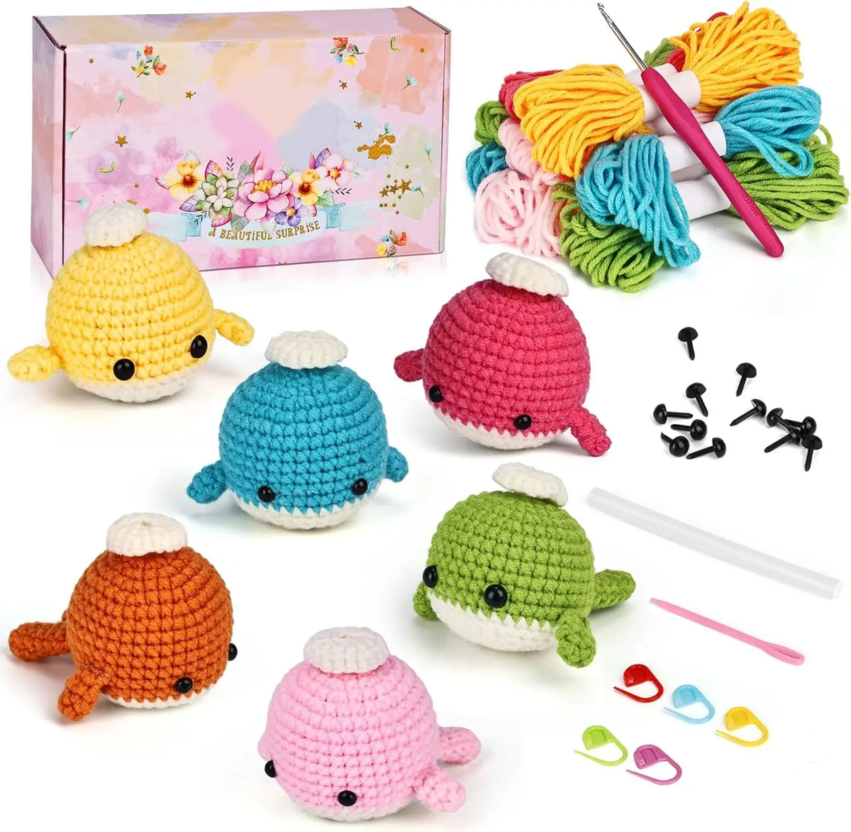 Six colorful crochet whale examples with yarn, hooks, safety eyes and stitch markers.