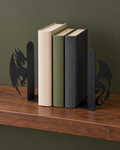 Two black dragon-silhouette bookends holding a row of books on a wooden shelf