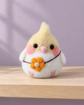Example of the finished felted cockatiel, with a yellow crest, pink cheeks and an orange flower